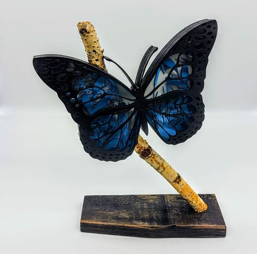 3d blue and black butterfly on a birch branch in a wood base